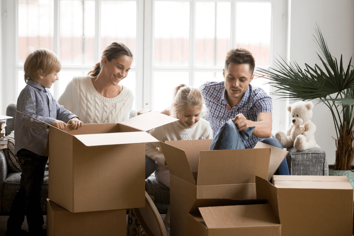 Family of four, two adults and two kids, unpacking boxes in a new modern home