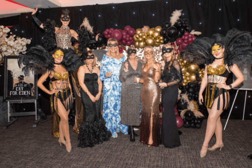 group of people in format attire with a performer on stilts in the background