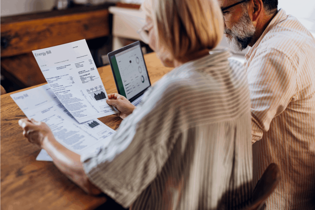 Couple sat at a table looking at energy bills with a tablet nearby