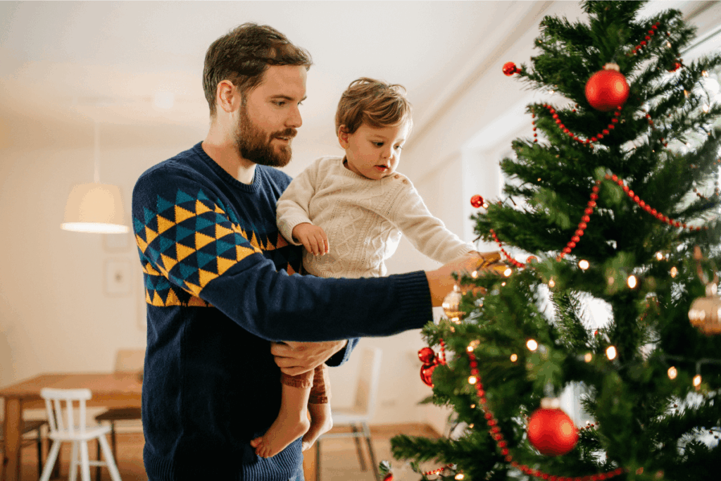 Man holding small boy decorating a christmas tree in a new home