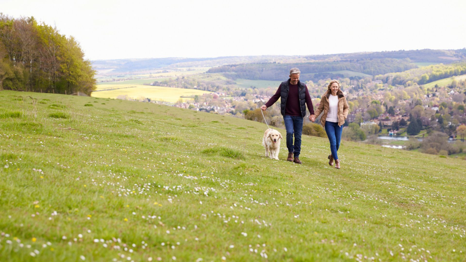 Couple smiling and walking their dog in the countryside