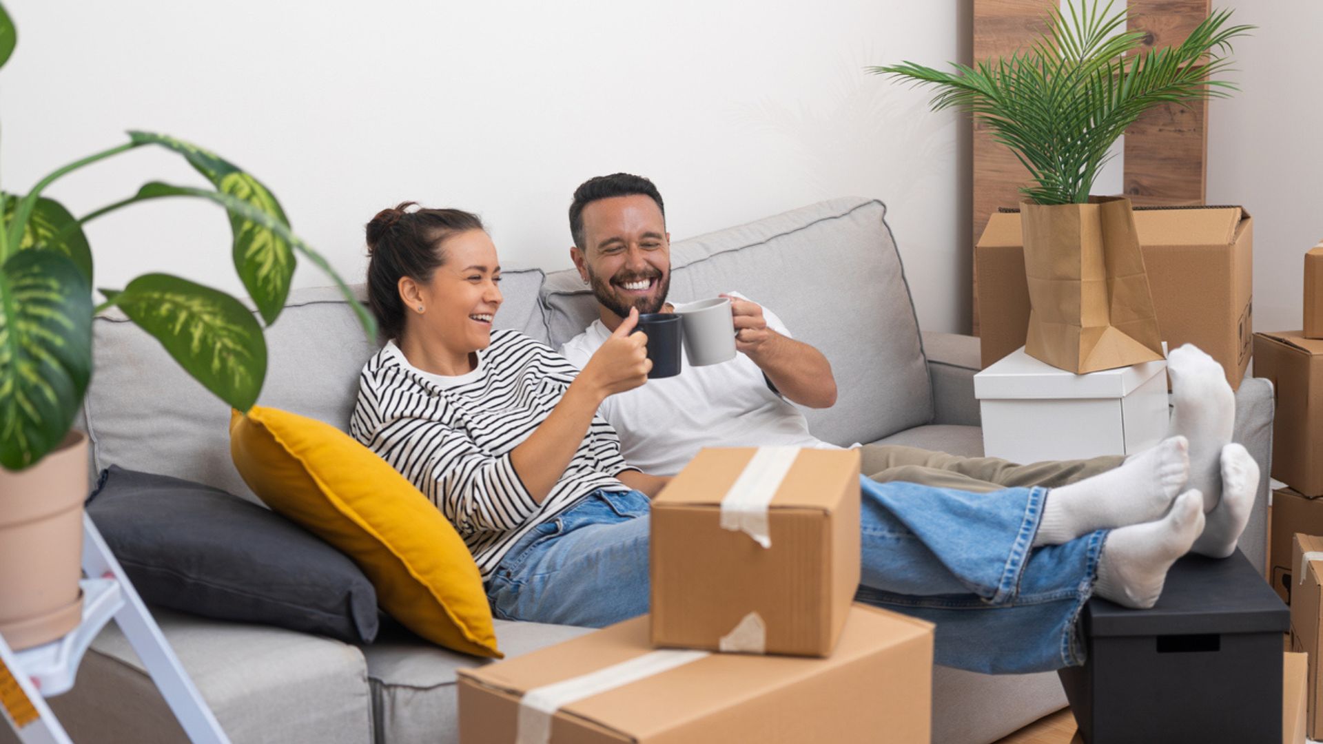 couple smiling on a sofa with moving boxes